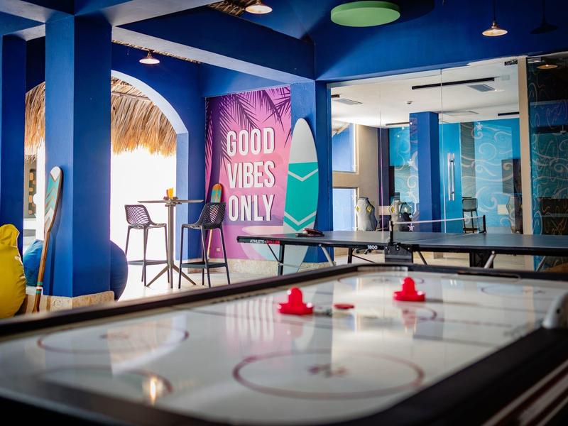 Salle de jeux bleu clair avec table d'air hockey et murs colorés.