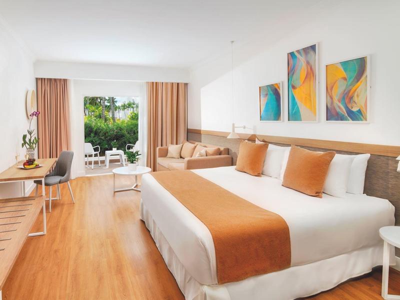 Chambre d'hôtel lumineuse avec lit double et balcon donnant sur la verdure.