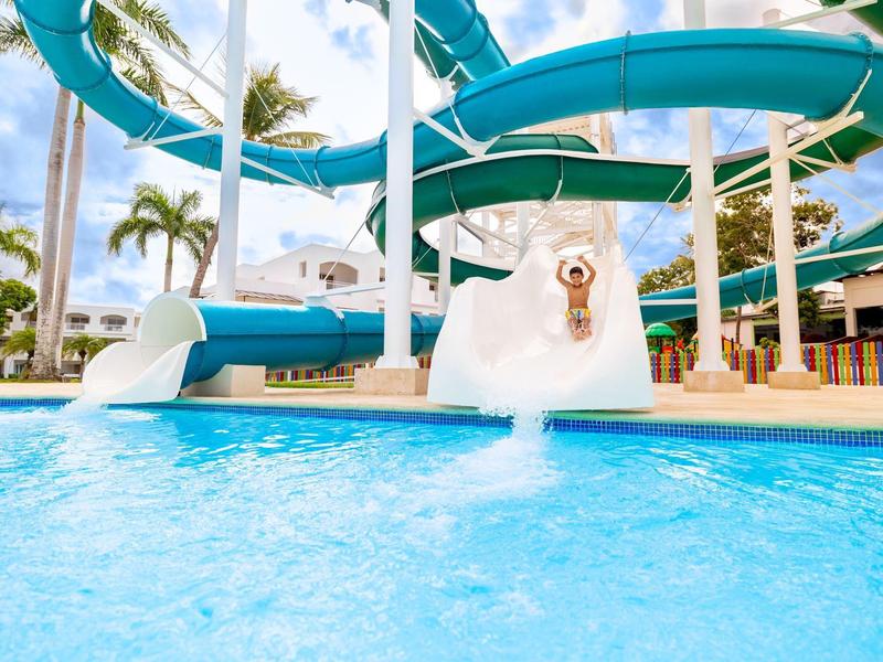 Parc aquatique avec un toboggan bleu menant à une piscine d'eau claire.