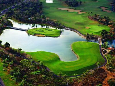 Großer Golfplatz mit grünen Fairways, Wasserhindernis und vereinzelten Sandbunkern.