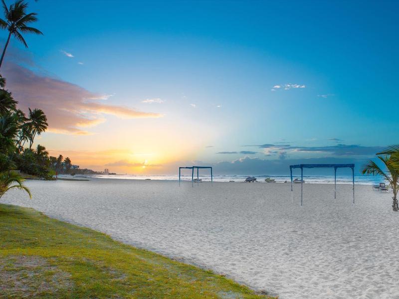 Beach with palm trees and swing frames at sunset