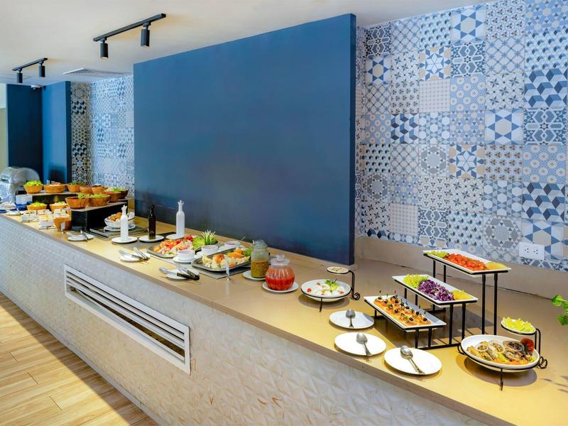 Buffet with various breakfast dishes in a modern hotel breakfast room.
