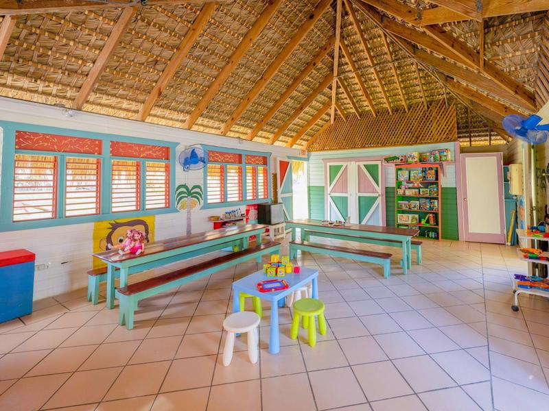 Bright, spacious kids' playroom with colorful furniture and thatched roof in a vacation resort.