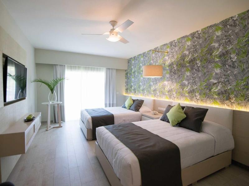 Modernes Schlafzimmer mit großen Betten, floralem Akzentwandpapier und hellem Fußboden.