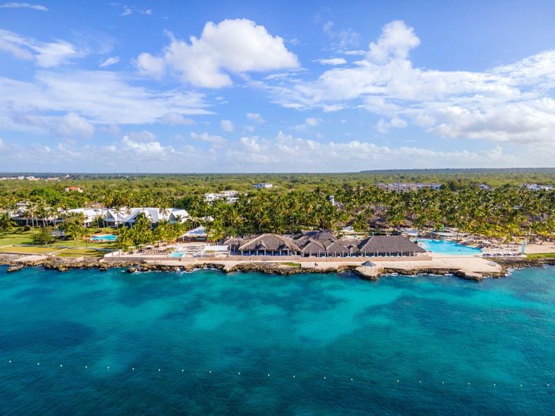 Resort on a tropical beach with clear blue water and a partly cloudy sky
