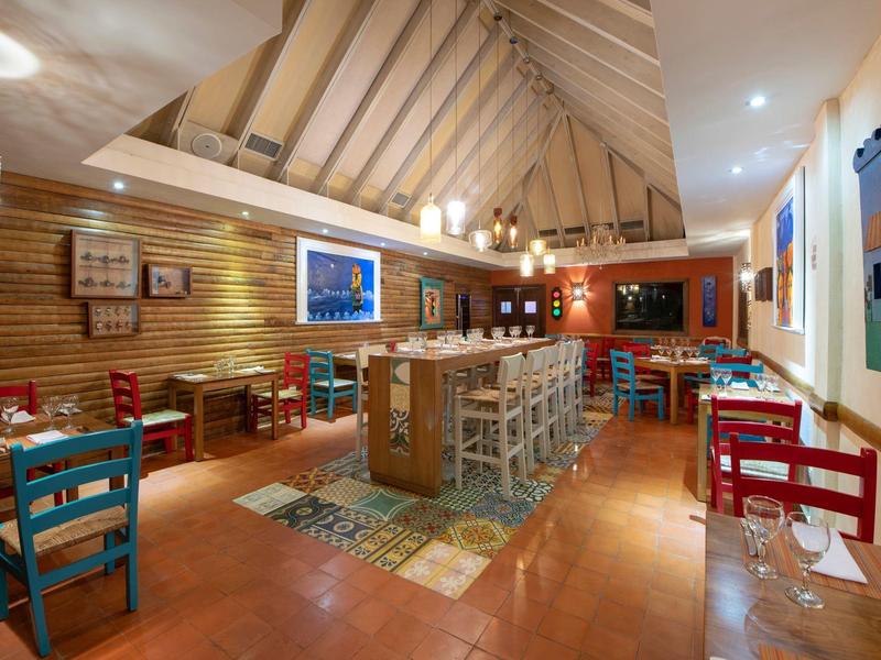 Intérieur d'un restaurant chaleureux avec des murs en bois et des chaises colorées.