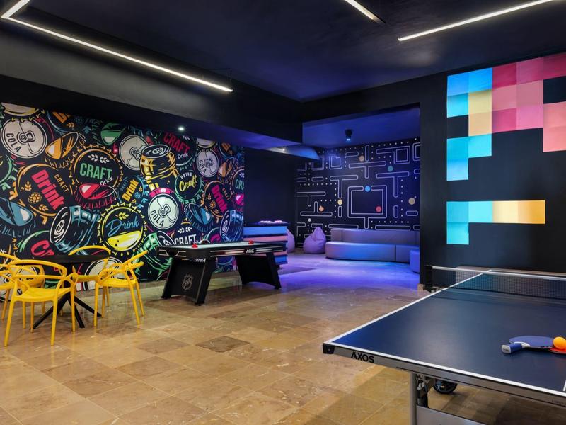 Sala de ocio moderna con ping-pong, air hockey y arte mural colorido en un ambiente elegante.
