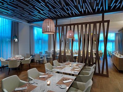 Modern restaurant met stijlvolle houten elementen en blauwe gordijnen op de achtergrond.