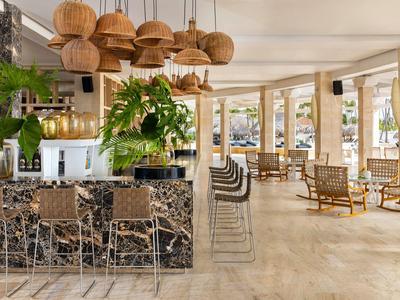 Lichte, moderne hotel eetruimte met marmeren bar, krukken en natuurlijk houten meubels.