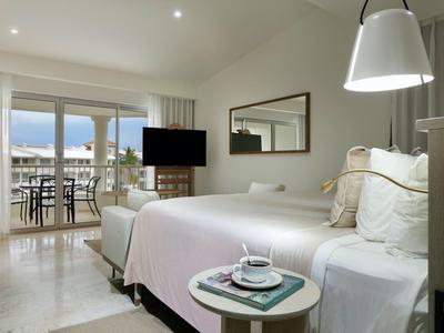 Moderne hotelkamer met tweepersoonsbed, tv, balkon en uitzicht op zee.