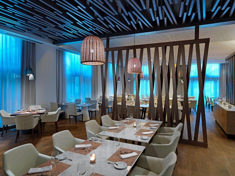 Modern restaurant met stijlvolle houten elementen en blauwe gordijnen op de achtergrond.