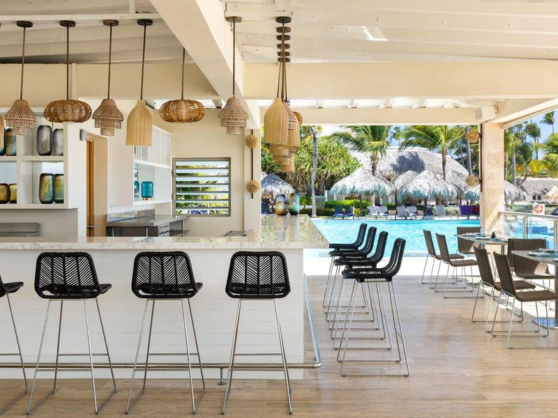 Moderne buitenbar met barkrukken en uitzicht op zwembad en tuin.