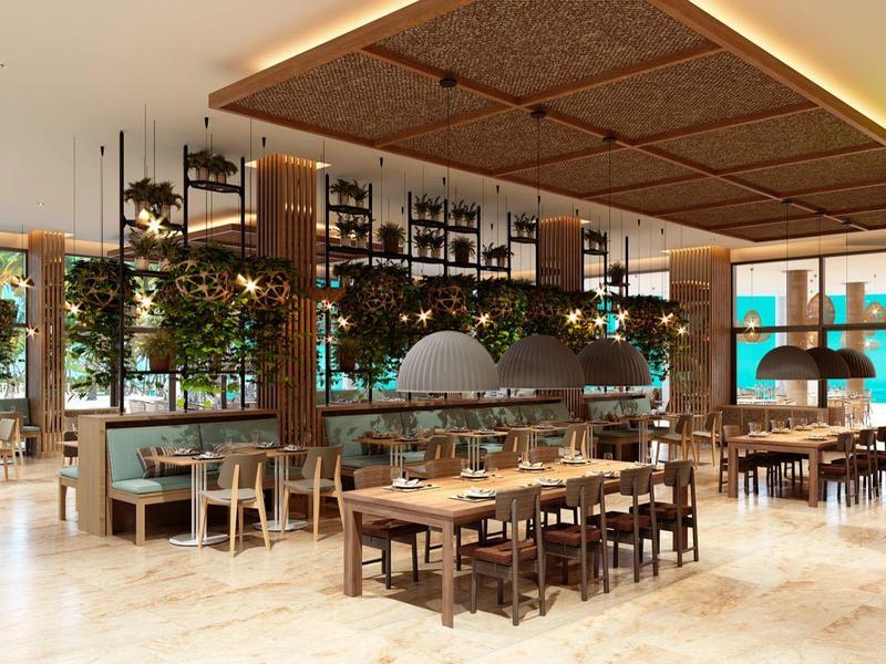 Moderne hotel restaurant met hout- en groene plantenaccenten en grote ramen met uitzicht op het water.