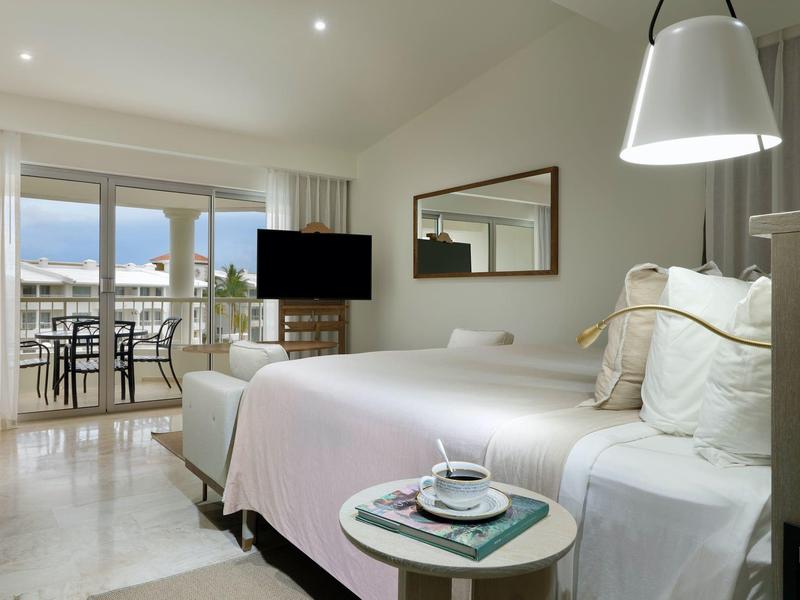 Moderne hotelkamer met tweepersoonsbed, tv, balkon en uitzicht op zee.