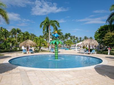 Mały okrągły basen z palmami i leżakami pod niebieskim niebem w tropikalnym kurorcie.