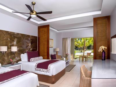 Modern eingerichtetes Hotelzimmer mit zwei Betten, Ventilator und Terrassentür zum Garten.