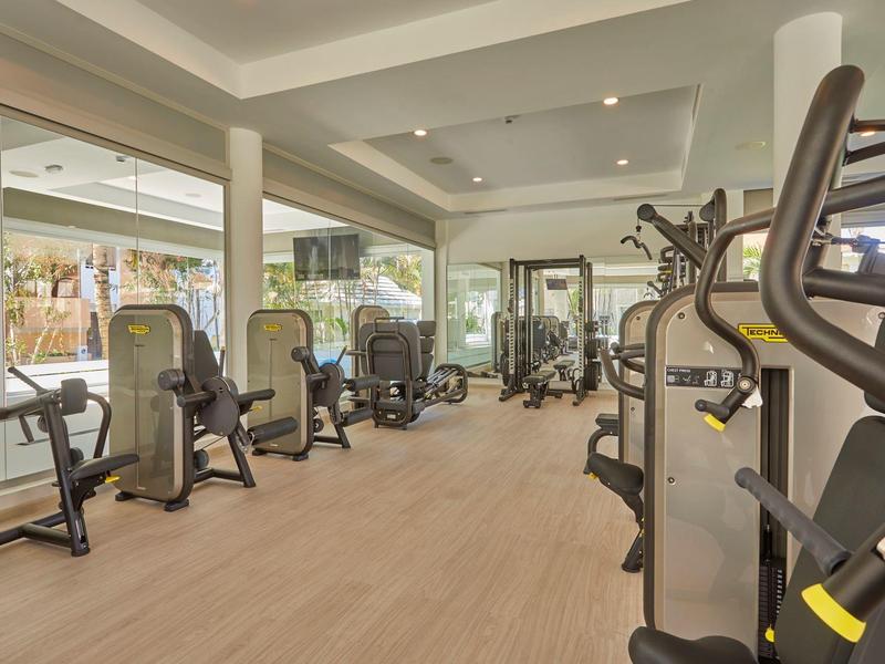 Gimnasio luminoso con varios aparatos modernos y grandes espejos.