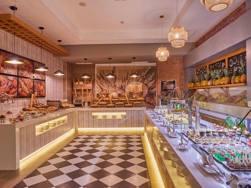 Área de buffet moderna con lámparas, pinturas y variedad de alimentos.