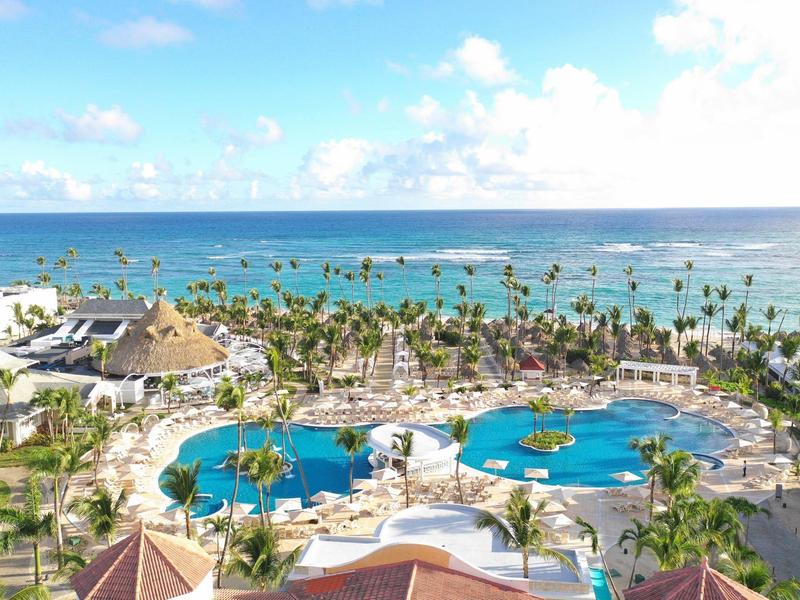 Vista de un resort tropical con piscinas, palmeras y el mar de fondo