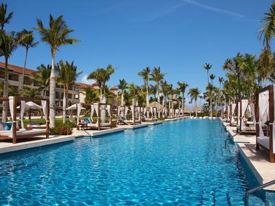 Groot buitenzwembad met palmbomen en ligstoelen in een zonnig resort.