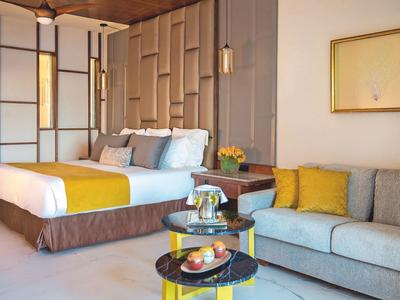 Moderne hotelkamer met comfortabel bed, bank en tafel met snacks en drankjes.