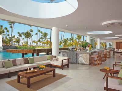 Moderne buitenruimte met bar en zwembad, omgeven door palmbomen en zonlicht.