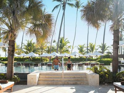 Blick auf Poolbereich mit Palmen und Sonnenschirmen bei klarem Himmel