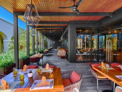 Moderner Außenbereich eines Restaurants mit Holztischen und bequemen Stühlen unter einem Holzdeckendach.