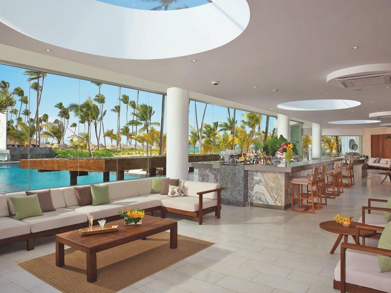 Moderne buitenruimte met bar en zwembad, omgeven door palmbomen en zonlicht.