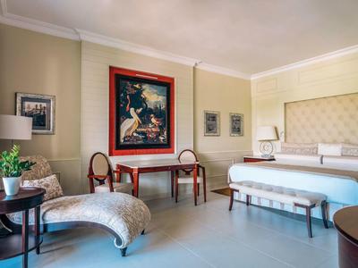 Elegant hotel room with large bed, table, chairs, and decorative wall art.