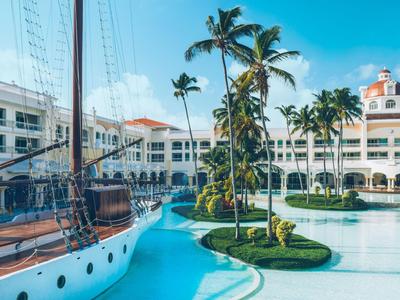 Hôtel de luxe avec piscine, voilier et palmiers sous ciel bleu