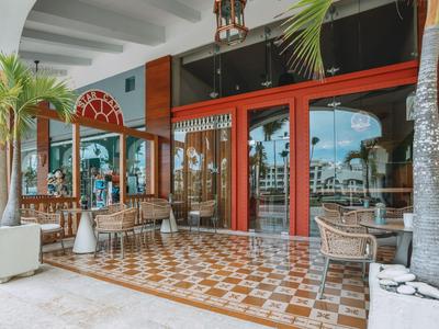 Area esterna di un hotel con posti a sedere, palme e pavimento a piastrelle a rombi.