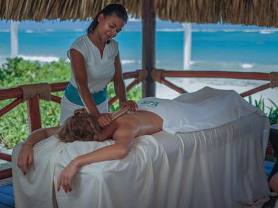 Vrouw krijgt massage op een comfortabele buitentafel met uitzicht op de oceaan.