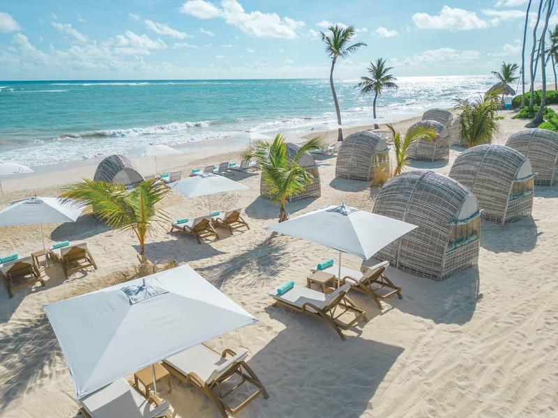 Beach with loungers, umbrellas, and small hut-style shelters by the sea