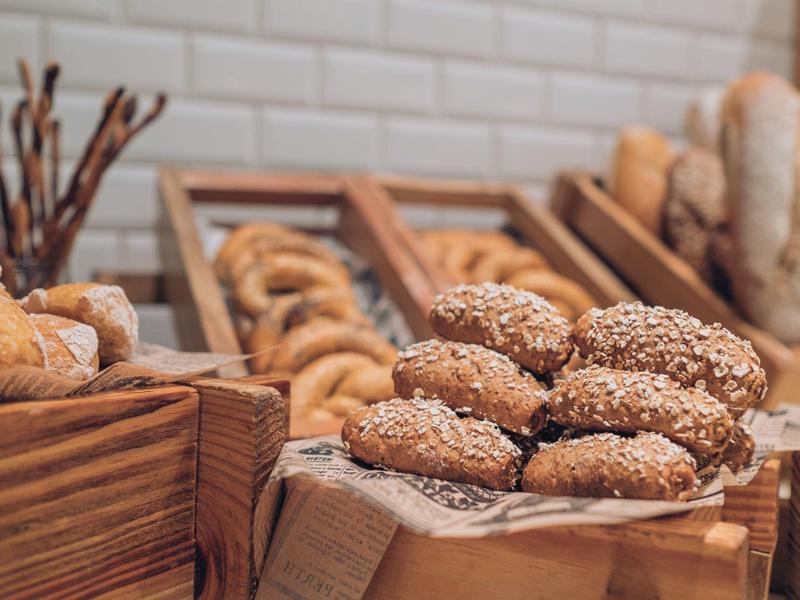 Various freshly baked breads and rolls in wooden containers in a bakery.