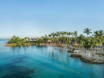 Costa tropicale con palme e acqua blu limpida sotto un cielo azzurro