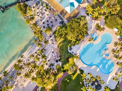 Luftaufnahme eines tropischen Resorts mit blauem Swimmingpool, Palmen und Sandstrand am Meer.