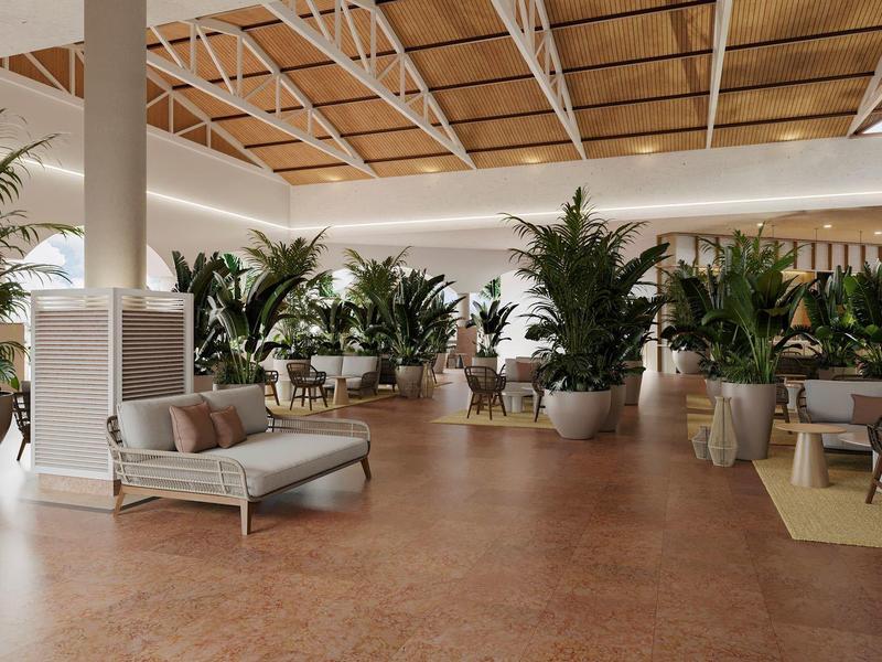 Großer Raum mit Holzbalkendecke, vielen grünen Pflanzen in Töpfen und hellen Sitzmöbeln.