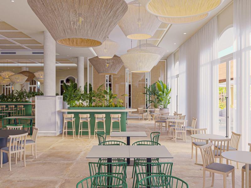 Heller, moderner Gastraum mit großen Fenstern, grünen Stühlen und hölzernen Details.