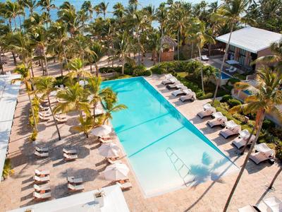 Groot buitenzwembad met ligstoelen en palmbomen bij een tropisch hotelresort.
