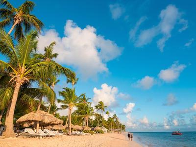 Strand mit Palmen und Sonnenschirmen unter blauem Himmel am Meer