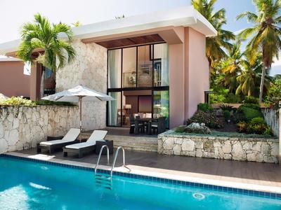 Moderne villa met zwembad, ligstoelen, parasol, palmbomen en tropische planten