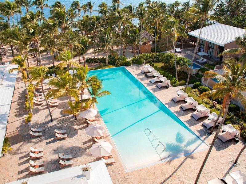 Groot buitenzwembad met ligstoelen en palmbomen bij een tropisch hotelresort.
