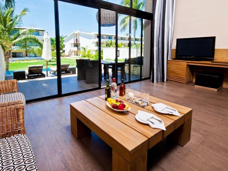 Moderne hotel eetruimte met witte muren, blauwe zitplaatsen, houten tafels en groene planten.