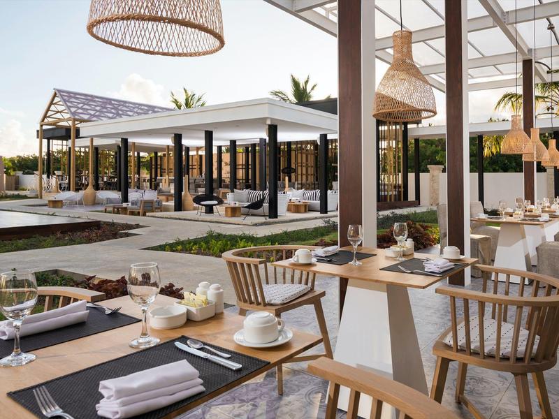 Modern restaurant buiten met houten meubels en overdekte zitgedeeltes bij daglicht.