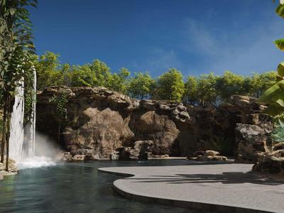 Duży basen z wodospadem i skałami w tropikalnym otoczeniu hotelowym pod niebieskim niebem.