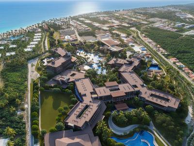 Luchtfoto van een resort met zwembad nabij zee omgeven door groen.