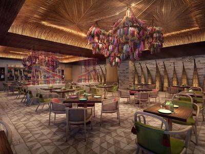 Elegant hotelrestaurant met moderne verlichting, groene stoelen en bloemenarrangementen aan het plafond.