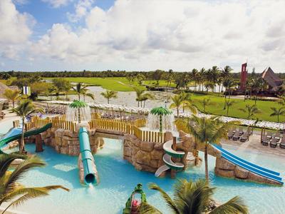 Waterpark met glijbanen en zwembad voor een groen landschap onder een blauwe lucht.