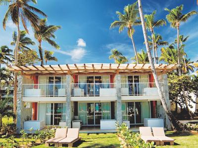 Breit wit zandstrand met palmbomen en helderblauwe zee onder een heldere lucht.